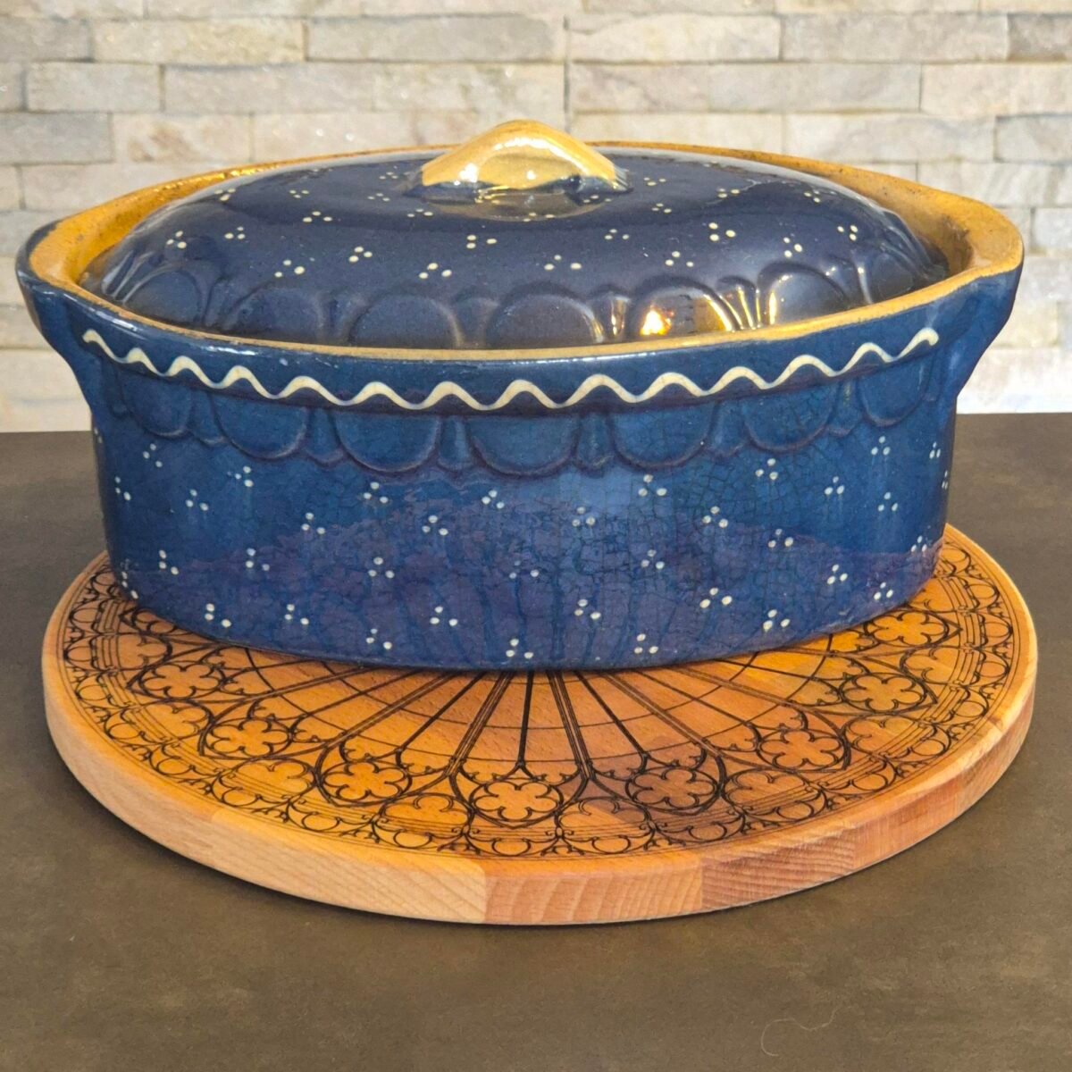 Rosace en bois inspirée de Strasbourg utilisée comme dessous de plat sous une poterie bleue