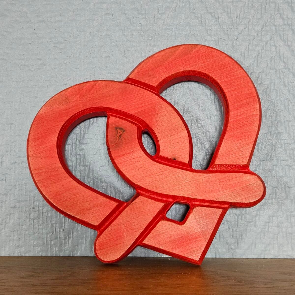 coeur bretzel rouge posé contre un mur gris