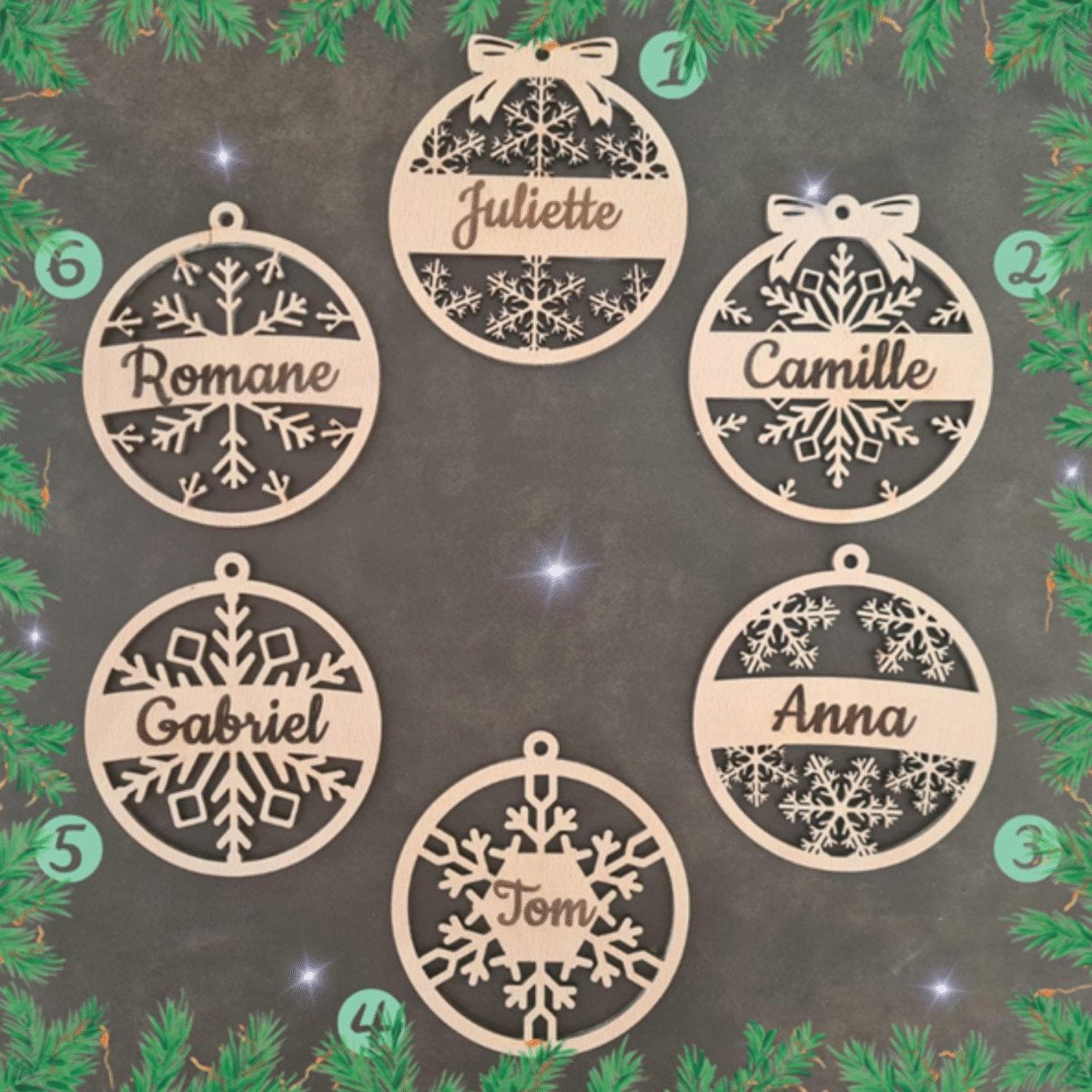 Présentation de plusieurs ornements de Noël en bois disposés sur fond pailleté, avec des prénoms comme "Romane", "Juliette", "Camille", "Gabriel" et "Anna" ornés de divers motifs de flocons et décorations découpés au laser