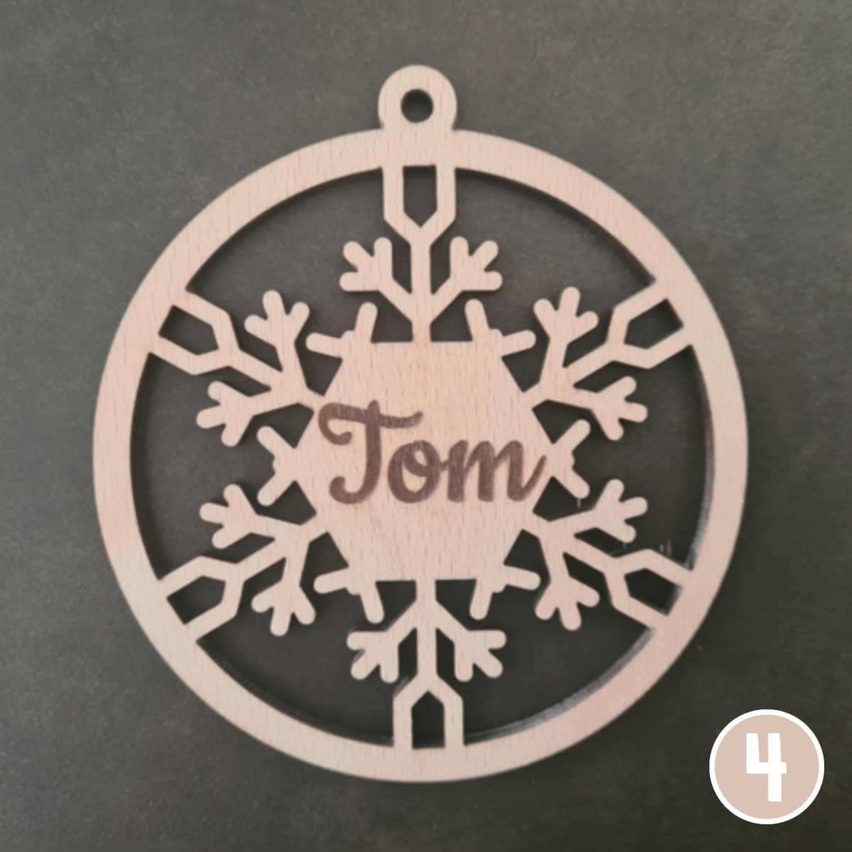 Ornement de Noël circulaire en bois avec le prénom "Tom" centré sur un grand motif de flocon de neige, avec design ajouré détaillé et trou de suspension en haut